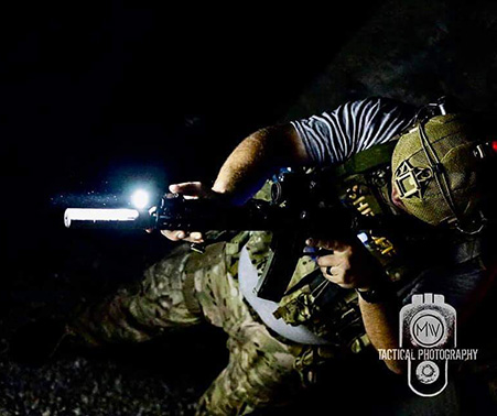 Matt Roberts holding a rifle with a flashlight at night time