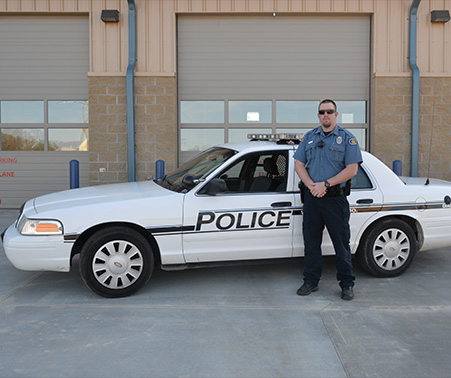 Matt Roberts in his West Plains Police uniform next to a police car